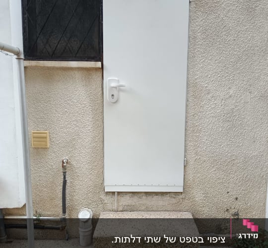 דלת לבנה עם ידית על קיר חיצוני